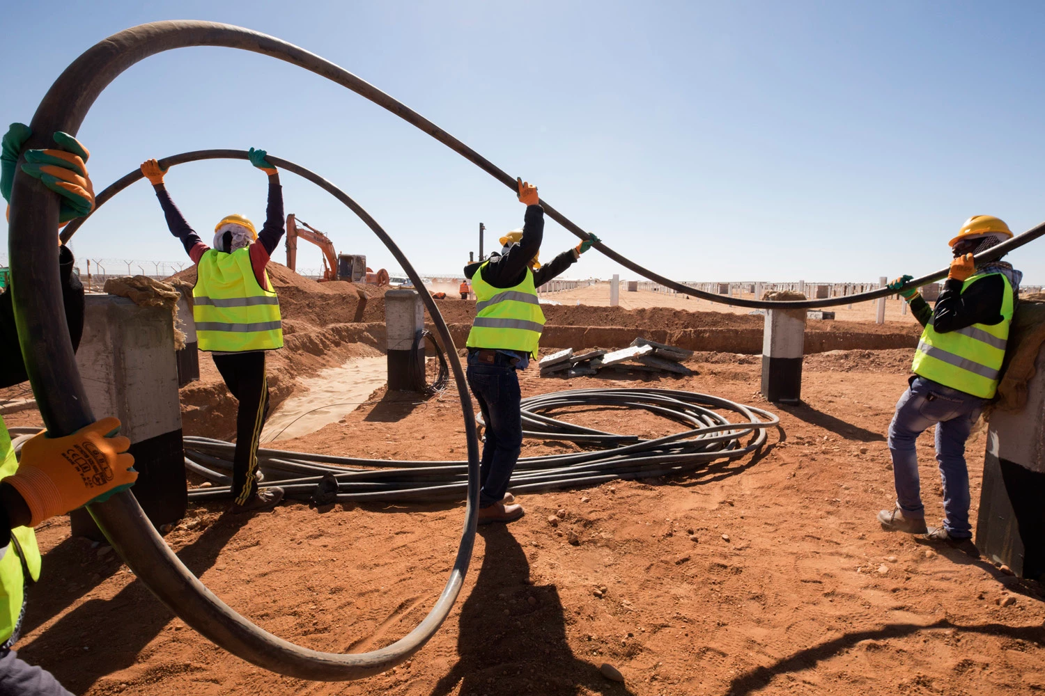 Mega Benban workers carry medium voltage cables in the Benban Solar Park in Benban, Egypt on December 11, 2018. Photo © Dominic Chavez/International Finance Corporation